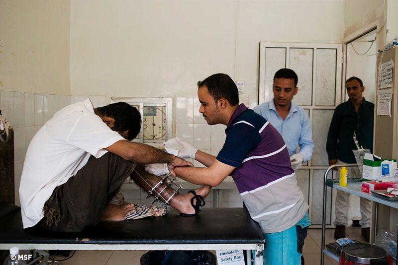 Nurse Abdul Aziz al Aury washes out a man’s leg wound, infected due to long periods of sitting at home with external fixation for a broken leg.