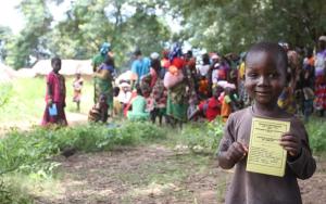 A child holding up their vaccination card