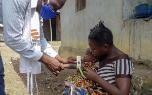 An MSF staff member measuring a child's arm for malnutrition