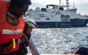 MSF Cultural Mediator Nejma helps a survivor on one of the Rigid Hull Inflatable Boats
