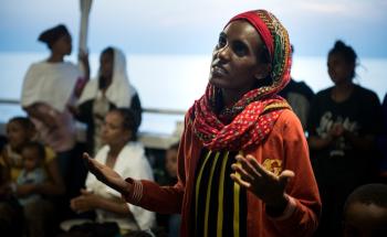 An Eritrean woman singing a prayer with other women and children