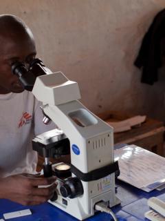 An MSF doctor looks through a microscope to check for Sleeping Sickness
