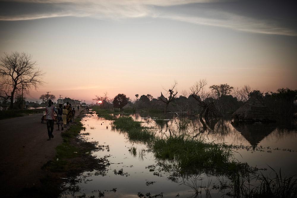 People walk along a flooded road in Bentiu