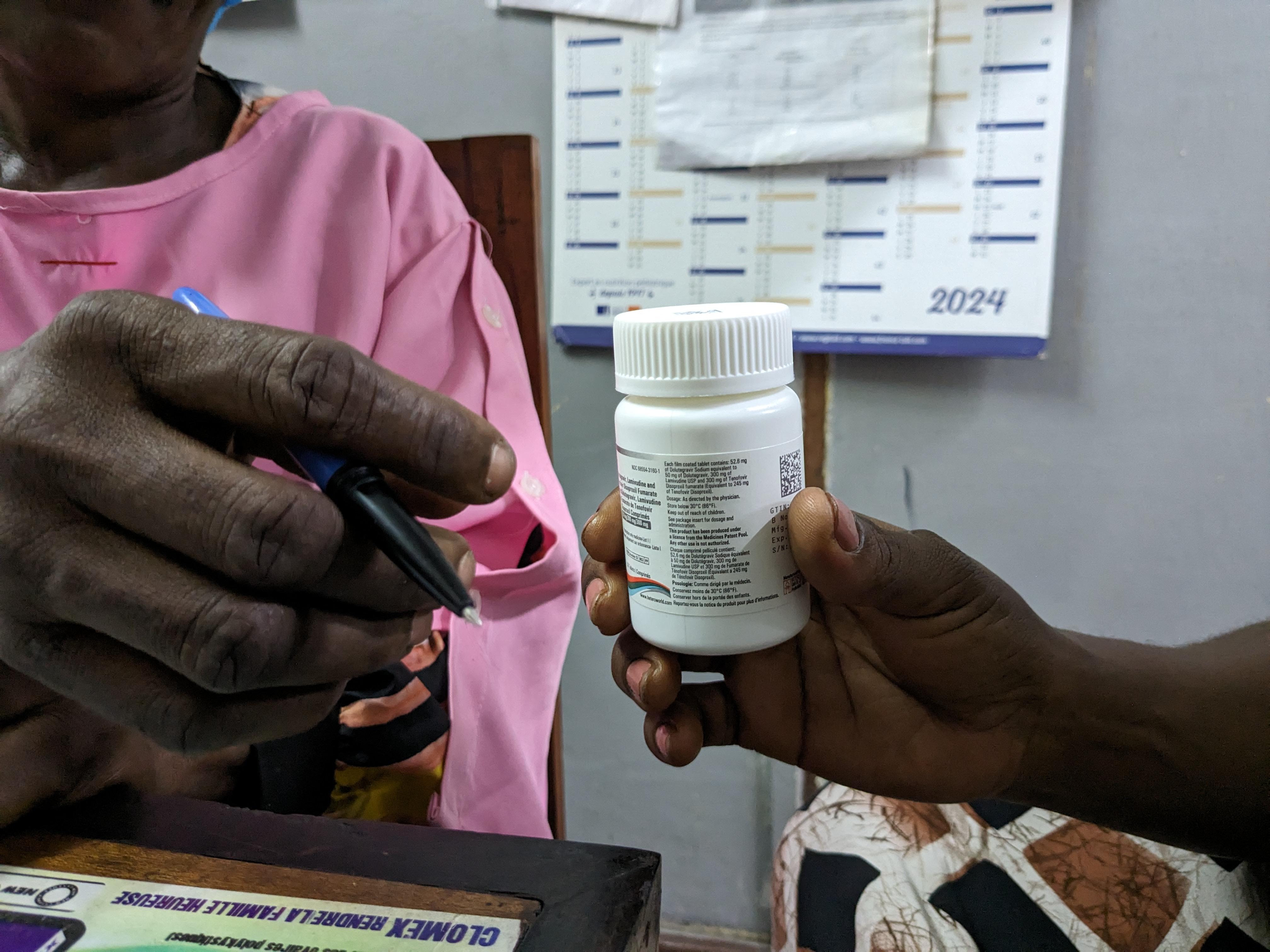 A doctor hands over a pill bottle for medication for HIV/Aids. 