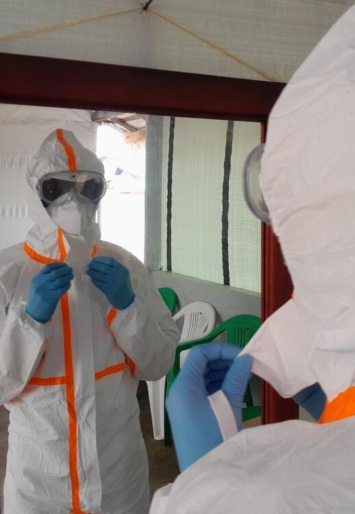 a nurse is being dressed up with full Personal Protective Equipment. War and conflict have a devastating impact on health.