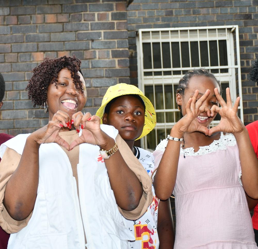 Relative showing the teen mum how to make hand love sign