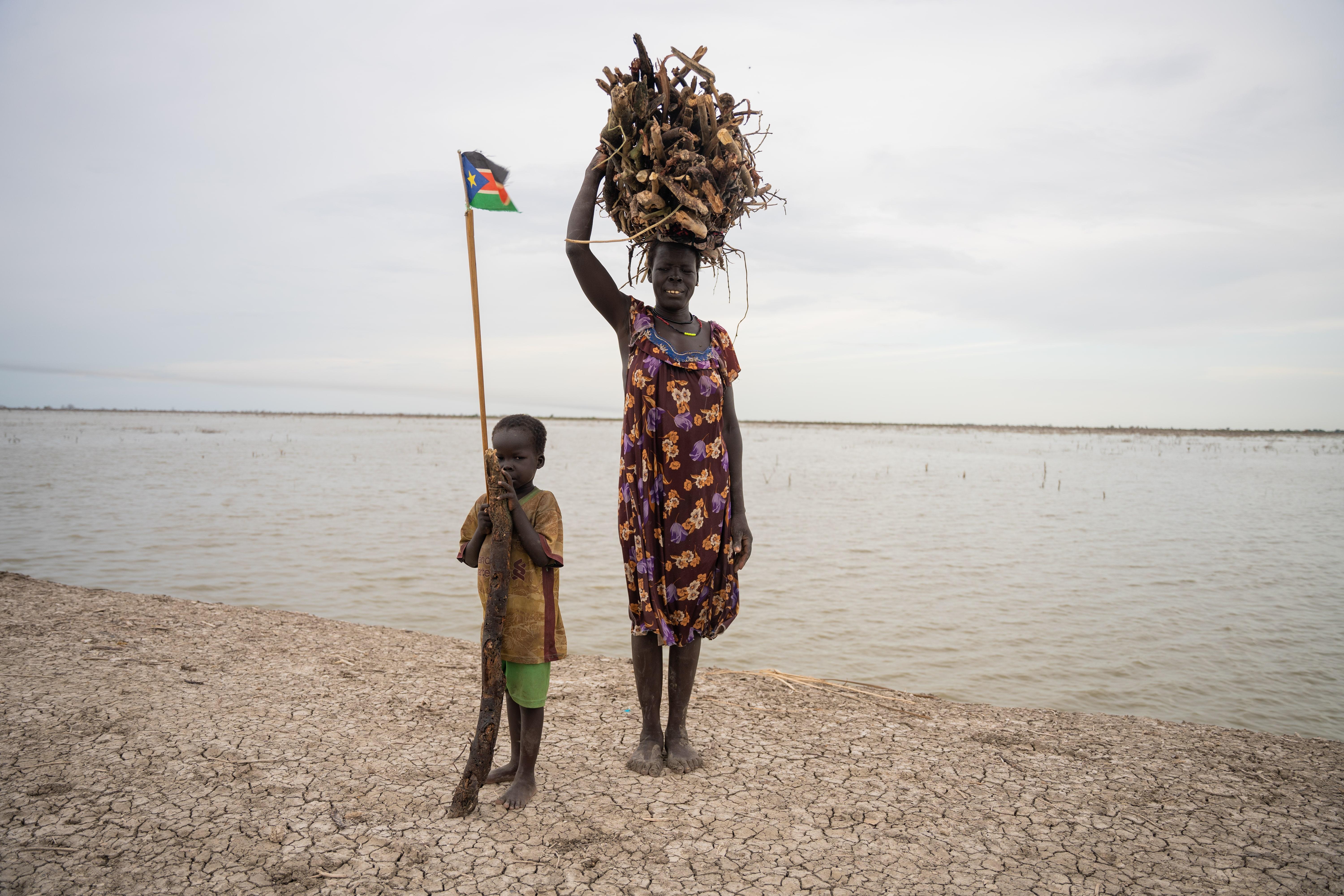 Life-saving care in Sudan: Roda Nefazal Mnot, 45 year-old carrying the wood she collected from the floodwaters for firewood. Her 5-year-old son follows her everywhere.