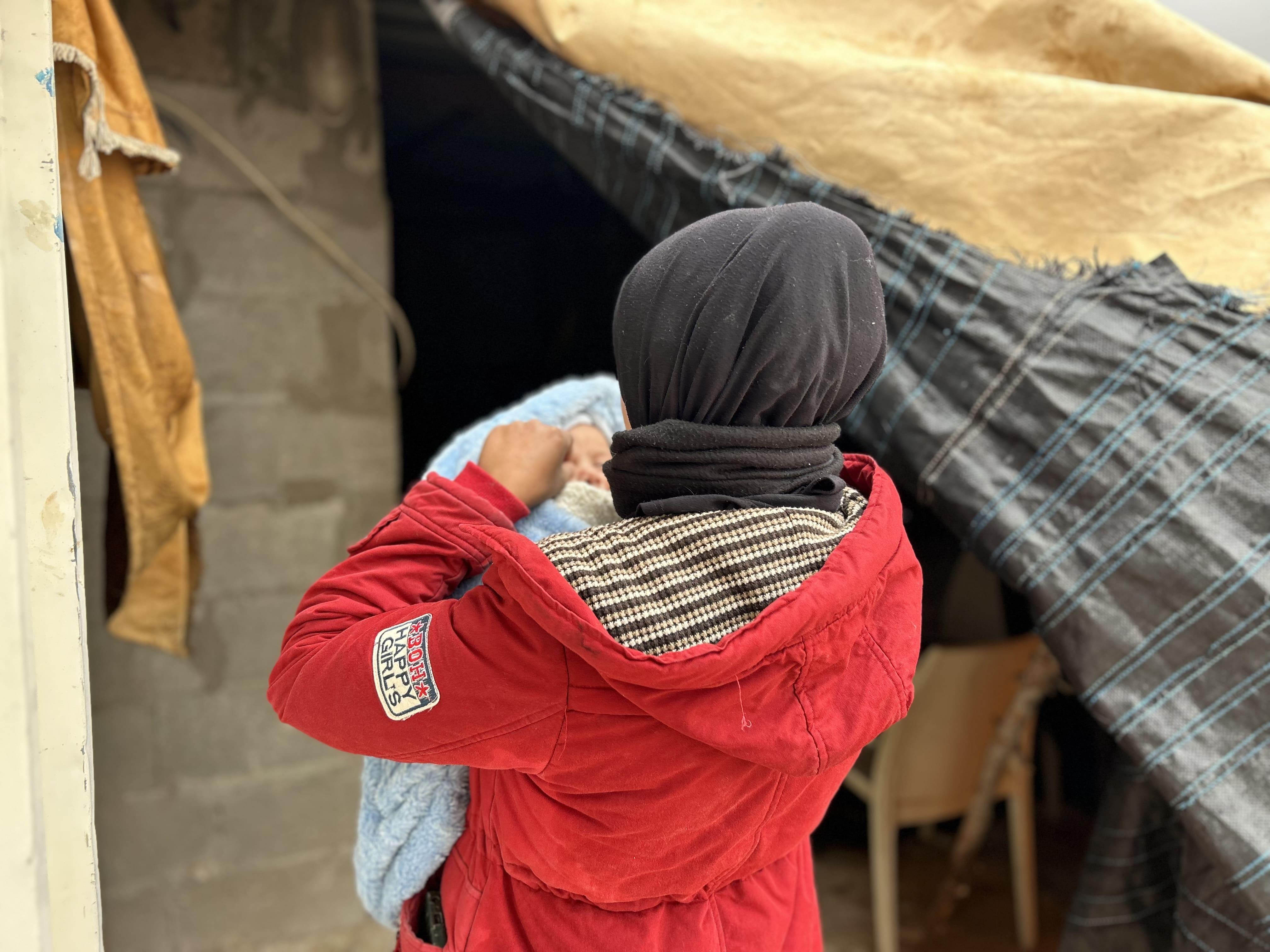 Palestinians in Hebron: Nesma*, a Palestinian mother holds her newborn son, covered in multiple blankets to keep him warm in the cold of the winter, in south of Hebron, West Bank, Occupied Palestinian Territories.