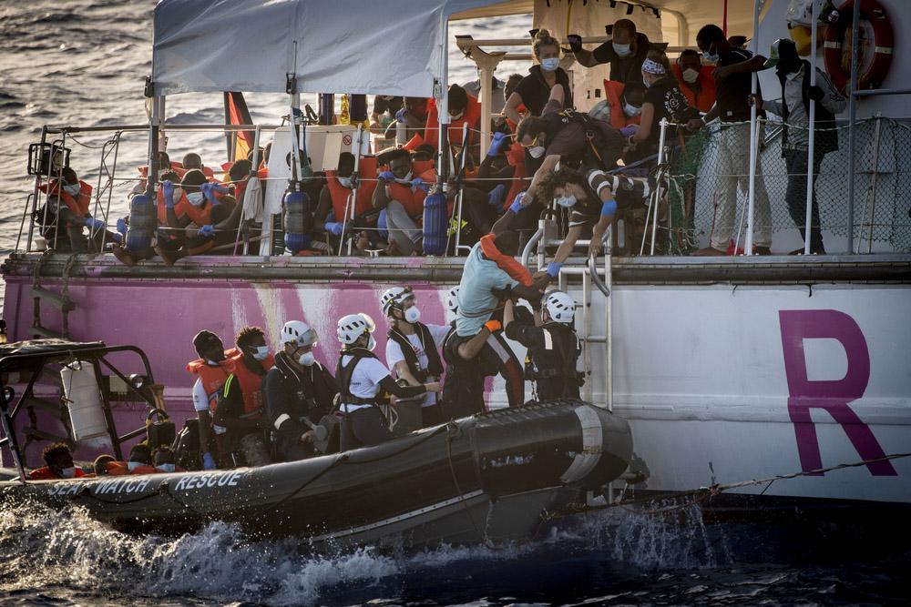 People being lowered into a smaller boat