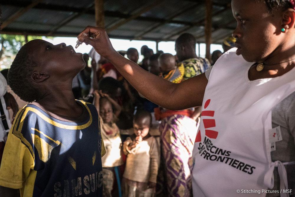 A young man receives his vaccination from a local MSF staff member.